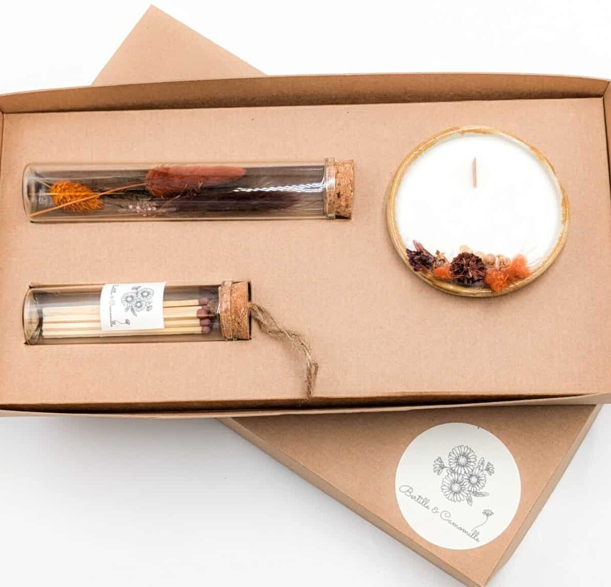 Coffret cadeau avec bougie en fleurs séchées parfumée tonka, fioles d'allumettes et éprouvette de fleurs séchées aux couleurs orange et marron, le tout dans une jolie boîte en kraft.