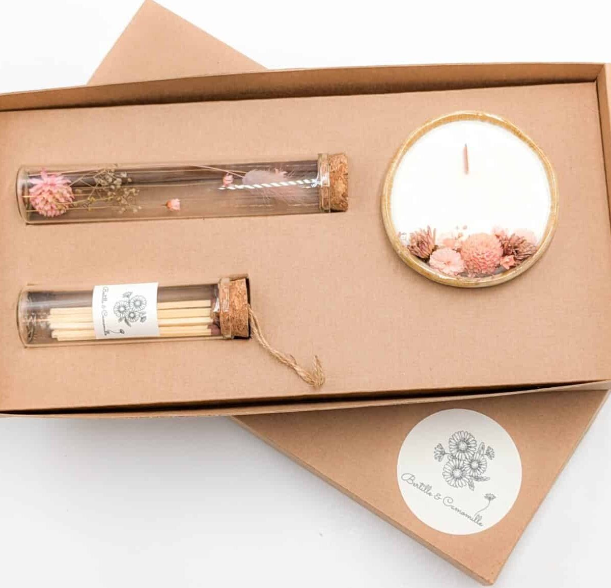 Coffret cadeau avec bougie en fleurs séchées parfumée fleur de tiaré, fioles d'allumettes et éprouvette de fleurs séchées aux couleurs roses, le tout dans une jolie boîte en kraft.